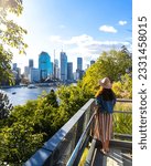 Small photo of beautiful woman in a hat enjoying panorama of brisbane cbd from kangaroo points; brisbane skyline and river seen from famous cliffs, holidays in brisbane