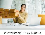 Portrait young attractive asia female owner startup business  work happy with box at home prepare parcel delivery in sme supply chain, procurement, omnichannel commerce online concept.