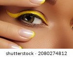 Small photo of Beautiful macro close-up of female Eye with bright yellow Eyeliner Makeup. Neon Disco make-up and Fashion Manicure. Summer beauty styleCloseup macro shot of fashion liner eyes visage