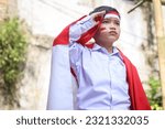 Indonesian young boy wearing uniform and indonesian flag gesture saluting.  Ceremony of Indonesia Independence Day. 