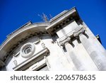 Small photo of Old building with pillars and plants growing near roof. Vibrant, blue sky background. Authoritative official style architecture.