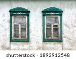 Two wooden windows in abandoned old countryside house. View of an old-fashioned house in the village. Close-up.