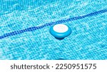 Small photo of Floating dispenser in the pool with a chlorine tablet inside to correct the ph of the water before swimming. Blue and white chemical dosing float for chlorine tablets