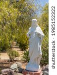 Small photo of Santa Inez, CA, USA - April 3, 2009: San Lorenzo Seminary. Sacred heart white statue in garden with green foliage in back under blue sky.