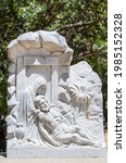 Small photo of Santa Inez, CA, USA - April 3, 2009: San Lorenzo Seminary. Station of the Cross number 14 white marble statue. Jesus laid in tomb. Green foliage in back.