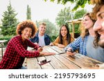 Small photo of Group of young people sitting in a cafe and smiling and looking theyr smartphone - Happy multiethnic group of friends talking using smartphones in pub