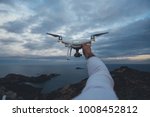POV shot of drone pilot or professional stock or nature photographer holding futuristic drone up in air in front of stormy skies, ready to fly technology into air and shoot aerial photos and videos