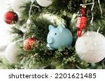 A small ceramic piggy bank with a Christmas tree. In the background of a New Year's gifts. Symbol of the new year 2023. Christmas card.
