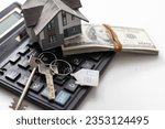 Small photo of A model house sitting with a calculator and twenty dollar bills on a white background with clipping path, mortgage calculator.