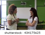 Small photo of Teenage student being told off by her teacher at school.