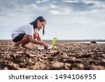 Small photo of Asian girl watering green plant in dry land,Crack dried soil in drought and ,Climate change from global warming.