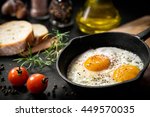 Fried eggs in a frying pan with cherry tomatoes and bread for breakfast on a black background.