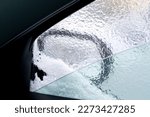 View of the side mirror of the car through the icy glass