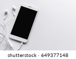 smartphone and earphone on white table with over light in the background