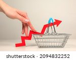Small photo of The fingers of a woman's hand step up the arrow of a chart lying on a shopping basket. Crisis and rising commodity prices concept
