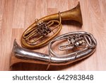 Small photo of two old rusty alto saxhorn on wooden background.