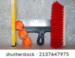 Small photo of repair and construction. repair tool set. putty knife, brush broom, bushings for sockets and building level. socket box with spatula and measuring balance level, fetlock on damaged wall background.