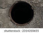 Small photo of Sewer hatch without lid. isolated on black background. dark hole, pit. top view. concrete floor.