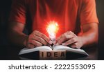 Small photo of Young man holding a light bulb placed on a book, finding new ideas, including applying things around him to make the most of it.the emergence of new innovations from reading