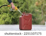 Small photo of A man fills jerry cans at a gas station. A man fills gasoline in a canister at a gas station. Pouring gasoline into a canister. Collecting funds to buy fuel.