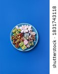 Small photo of Middle Eastern sweets. Turkish delight with pistachios nuts on plate over blue background. Top view. Copy space. Arab dessert, rahat lokum, sherbet, nougat, churchkhela, cookies. Flat lay