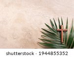 Palm Sunday concept. Wooden cross over palm leaves. Reminder of Jesus sacrifice and Christ resurrection. Easter passover. Eucharist concept. Christianity symbol and faith.