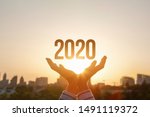 The concept new 2020 year. Hands show 2020 on the background of sunset.