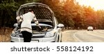 Small photo of young woman in a white jacket standing near the broken car. The girl opened the hood and look at the engine. Refit woman car