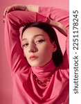 Small photo of Beautiful fashionable confident woman with blue eyeliner makeup, wearing trendy pink turtleneck, chunky chain. Close up studio portrait