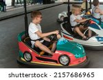 Boys driving bumper cars in an amusement park. Young drivers competing on mini car racing