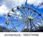 Low angle view of a ferris wheel in an amusement park with a blue sky background.  City park ferris wheel in Carousel Gardens Amusement Park, New Orleans City Park.