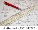Small photo of Vintage antique slide rule, logarithmic scale, calculations on paper, and pen.