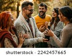 Small photo of Happy couple welcoming guests at the doorstep of their house who are bringing wine and gifts. The focus is on the man embracing one of the guests.