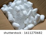 Small photo of Streamlined polystyrene pieces inside the mail package. Foam filler is a reliable way to pack items. Bulk - for the safe transportation of goods. The package is open. Polyethylene depreciation wrap.