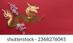 Small photo of Chinese New Year. Dragon cut out in gilt paper with plum blossom decoration on red background. Copy space. Top view.
