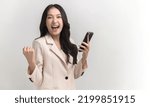 Small photo of Surprised young Asia lady using mobile phone with positive expression, smiles broadly, dressed in casual clothing and looking at camera on white background. Happy adorable glad woman rejoices success.