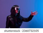 Small photo of Confused pretty awesome brunet lady in leather jacket trendy specular sunglasses touch invisible object posing isolated in blue violet color light background. Neon party Cyberpunk concept. Copy space