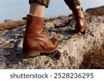 Solitary journey brown boots resting on large rock in field inspiration for adventure and travel exploration