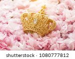 Small photo of Gold crown. Queen or king. Green leafs. lur background. Gift for woman. Bright pink flowers on white painted wooden planks. Selective focus. Place for text.