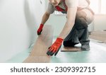 Small photo of Professional worker Installing laminated or wood parquet on floor, man holding wooden tile with sun light.