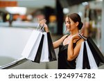 Stylish woman with shopping bags walks in the mall after shopping. Spring Style.  Consumerism, purchases, sales, lifestyle concept.