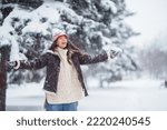 Beautiful woman standing among snowy trees and enjoying first snow. Holidays, rest, travel concept.