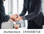 A suit-clad businessman shakes hands to sign a business partnership deal. Congratulation is a notion in business etiquette, as is the concept of shaking hands at an office meeting.