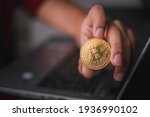 Businessman's hand holding a gold Bitcoin on a laptop. Make money with bitcoin, blockchain transfer