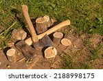 Small photo of The axes are lying next to the wooden chocks. Preparation of firewood for kindling. Stumps with axes, illuminated by daylight. Chop wood. Axes next to sawn logs.