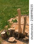 Small photo of Axes stand next to wooden chocks. Preparation of firewood for kindling. Stumps with axes illuminated by daylight. Chopping firewood. Axes next to sawn logs.