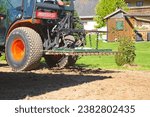 Small photo of Small tractor with tine harrow working on soil - harrowing