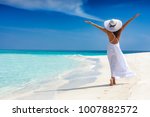 Happy traveller woman in white dress enjoys her tropical beach vacation