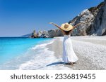 A elegant tourist woman in a white summer dress enjoys the beautiful beach of Lalaria, Skiathos island, Greece