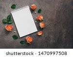 Small photo of Flat lay open notepad in a frame of rose flowers on a dark rustic background. Top view, copy space